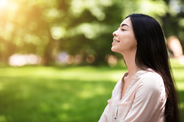 Portrait of relaxed asian girl breathing deeply with closed eyes in park